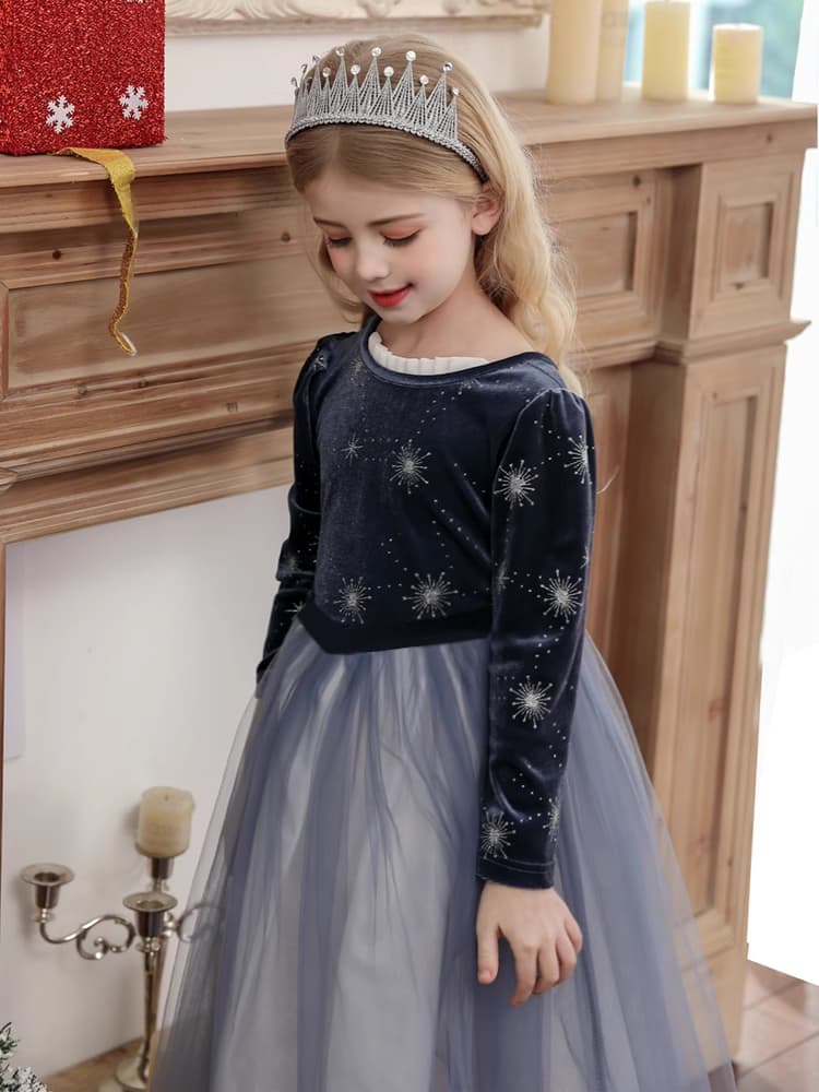 Young girl in a dark blue velvet top and gray tulle skirt , Dark Blue Long Sleeves Sparkle snow queen Princess Dress   with a silver tiara, standing in front of a wooden fireplace.
