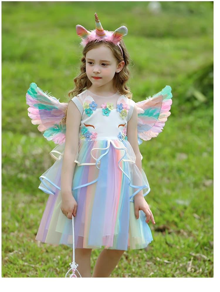 Child wearing a unicorn costume with wings and headband outdoors on grass