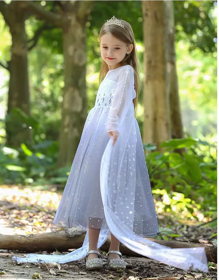 Young girl in a Sparkling Ice-Queen Inspired Princess costume With Cape  with a long train standing in a forest.