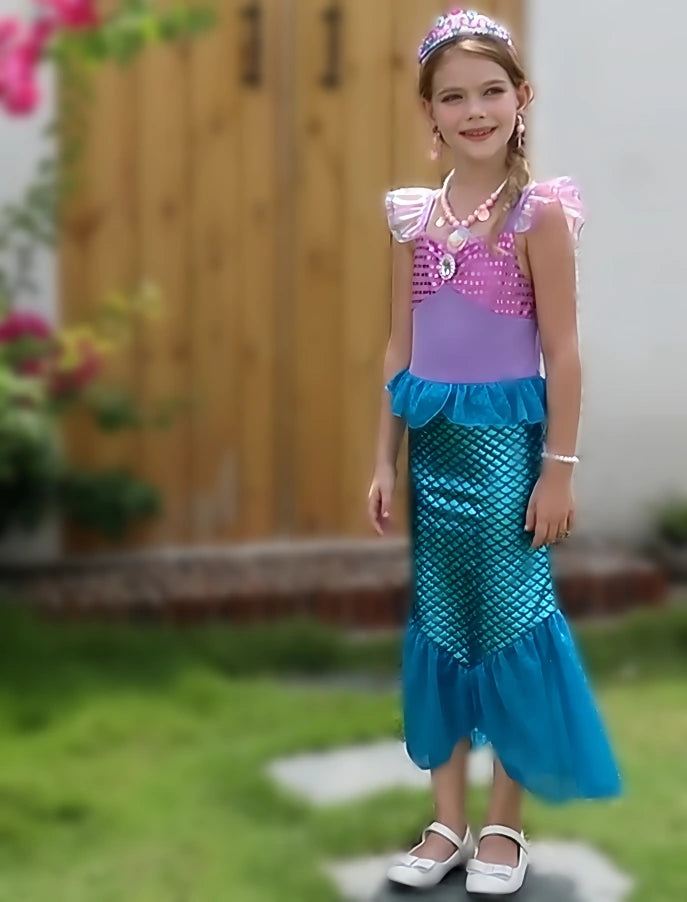 Young girl in a mermaid costume standing outdoors with a blurred background