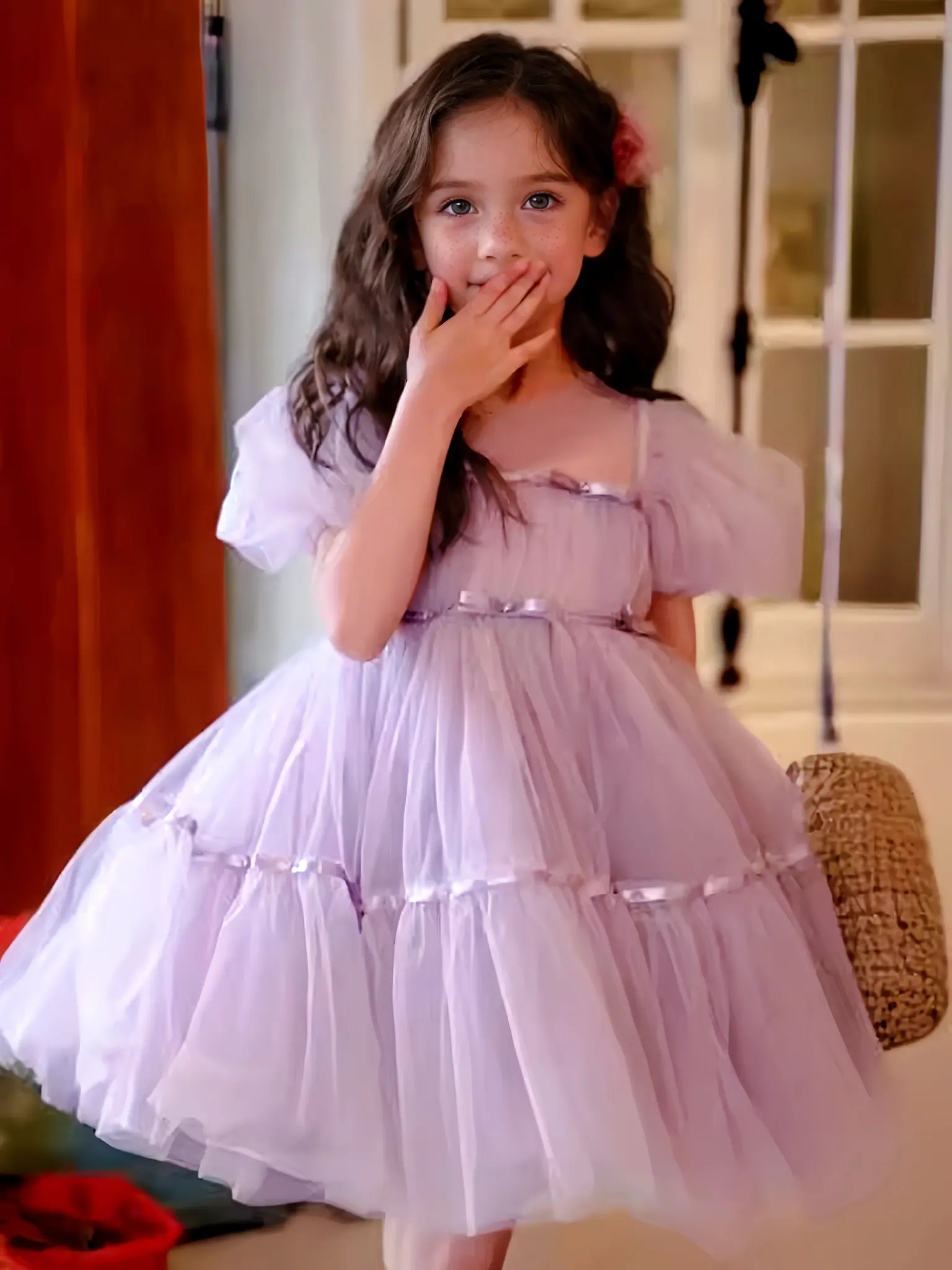Young girl in a light purple dress standing indoors.