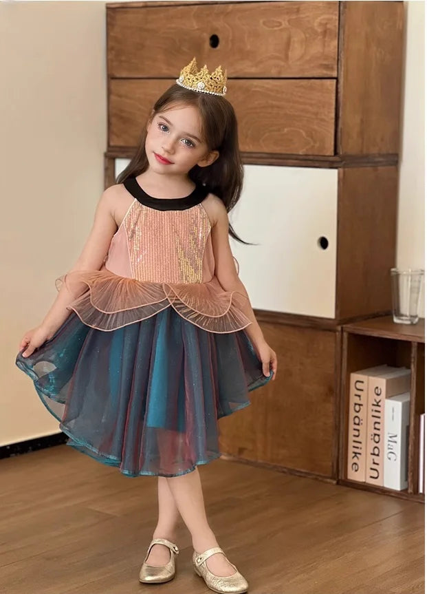 Young girl in a colorful Sleeveless Sea Princess Sequin Blue Tulle  Mermaid Dress  with a tiara standing in front of a wooden cabinet.