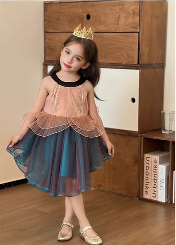 Young girl in a colorful Sleeveless Sea Princess Sequin Blue Tulle  Mermaid Dress  with a tiara standing in front of a wooden cabinet.