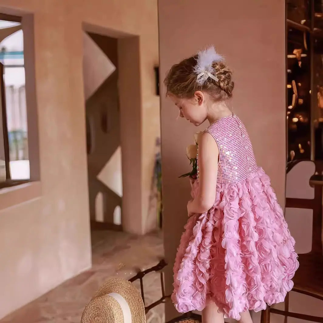 Young girl in a pink dress standing in a room with a decorative wall.