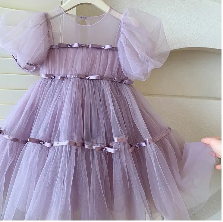 Lavender Purple Tulle Tutu Dress  with sheer sleeves and ribbon details on a hanger against a neutral background