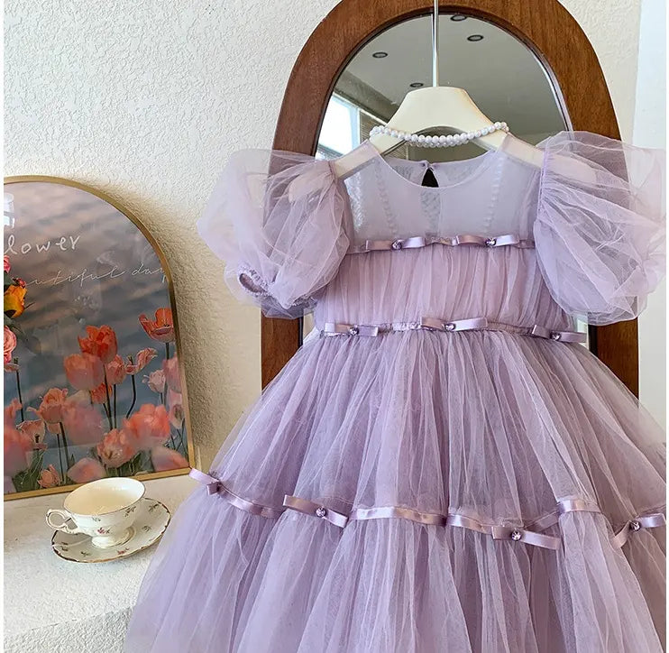 Lavender tutu tulle dress with puffed sleeves hanging in front of a mirror