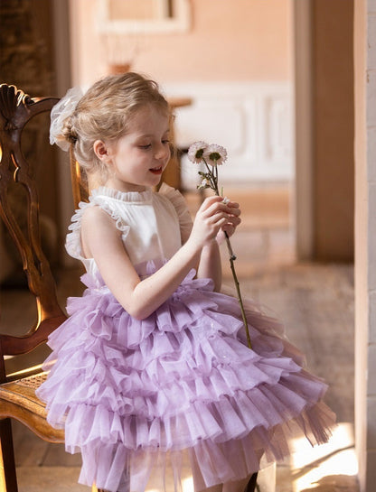 little girl in Lavender Layered Tulle Dress sitting and looking at flower