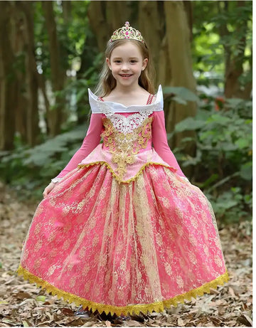 Young girl in a Princess Aurora Pink Lace Ball Gown with gold accents standing in a forest.