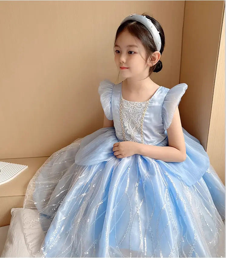 Young girl in a light blue airy Princess Dress  with lace details sitting on a couch.