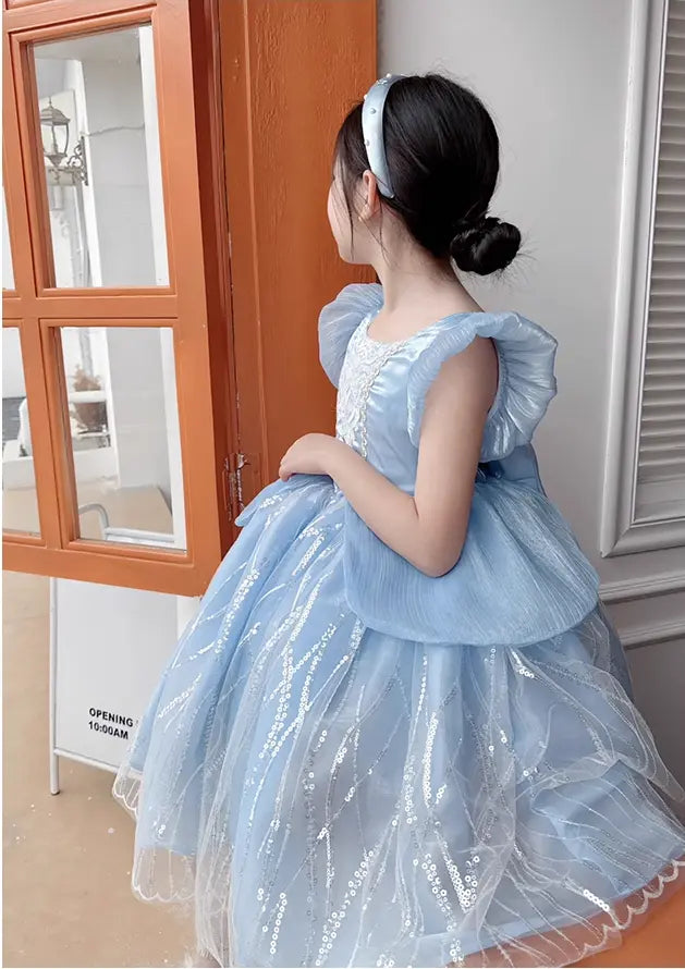 Child wearing a Blue Fairy Princess dress with puffed sleeves ,  in a room.