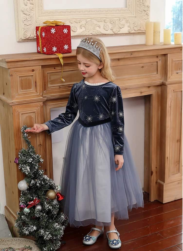 Young girl in a festive Dark Blue Long Sleeves Sparkle snow queen Princess Dress   standing next to a small Christmas tree in front of a fireplace.