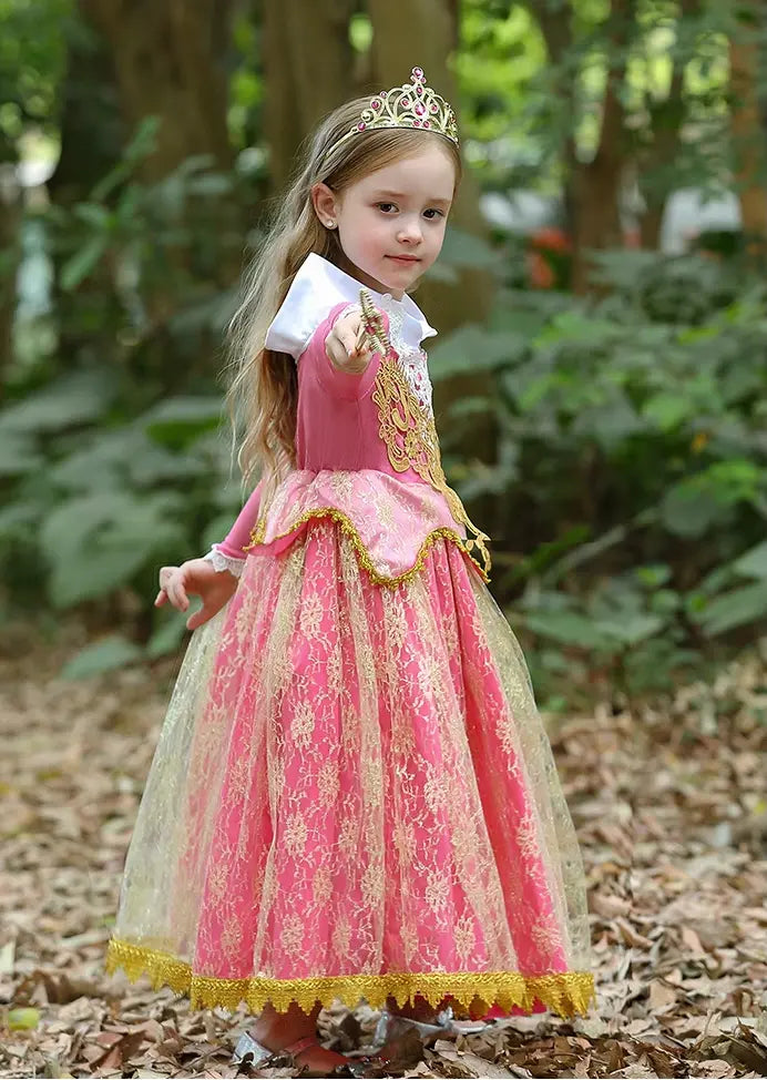 Young girl in a pink princess dress with a tiara standing in a forest.