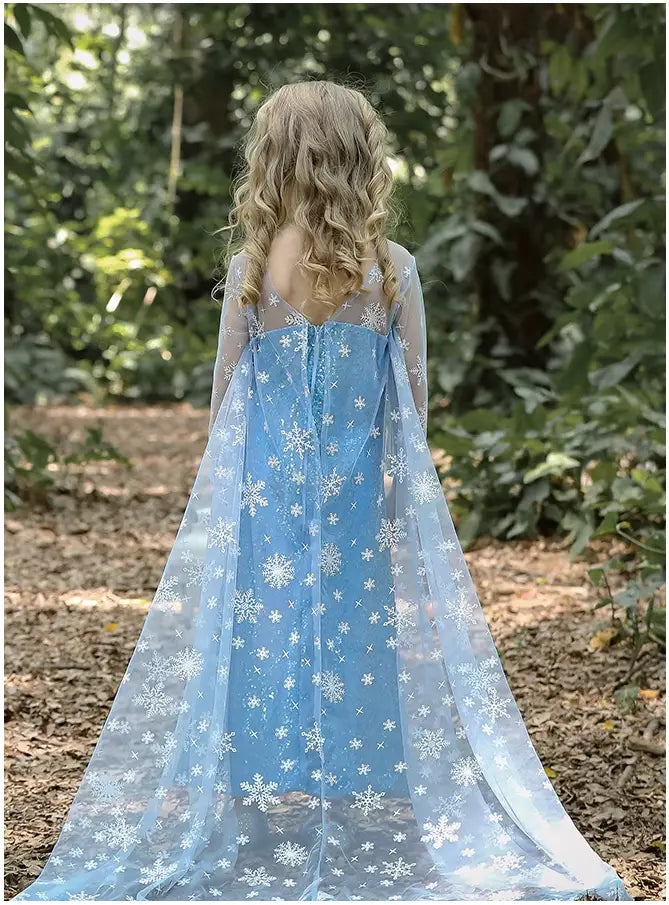 Person wearing a Glittering Winter Queen Blue Sequin Gown with Snowflake Cape  dress with snowflake patterns in a forest setting
