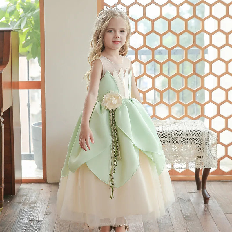 Young girl in a light green and white  Lily Flower Princess Dress with a flower accessory, standing indoors.