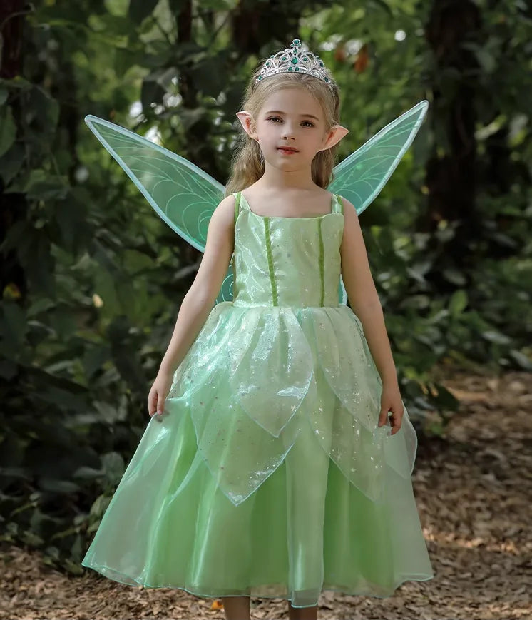 Child in a green fairy costume with wings and tiara standing outdoors.
