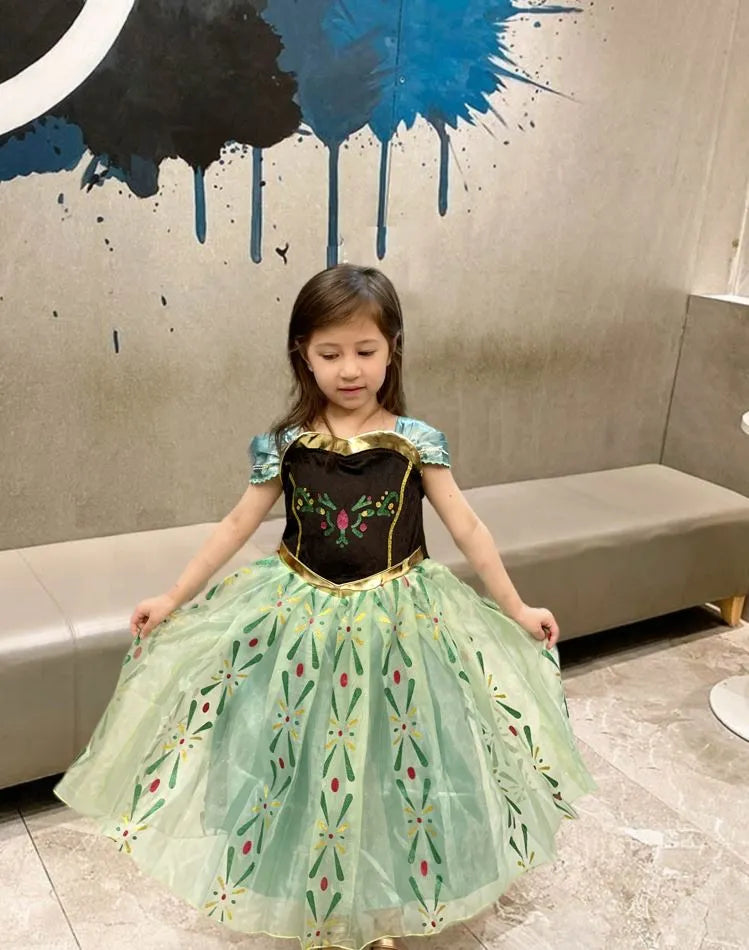 Child wearing a Green Tulle Ice Princess Anna Costume with floral patterns in a room with a decorative wall.