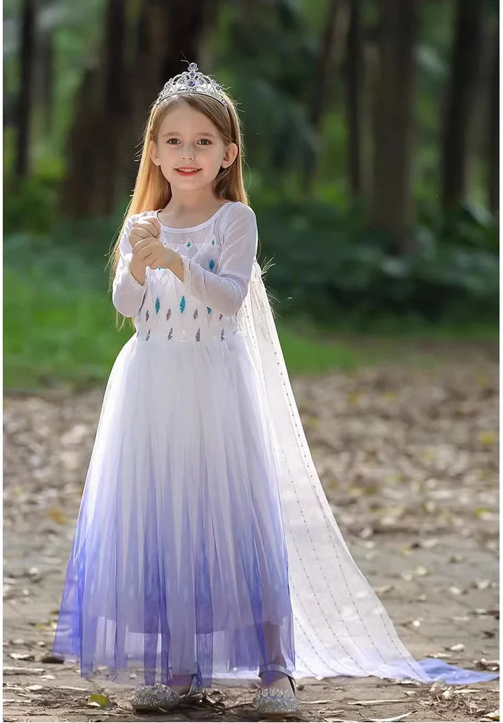 Young girl in a Kids Blue and White Ice Queen Princess Sequin Dress With Cape with a tiara standing in a forest.