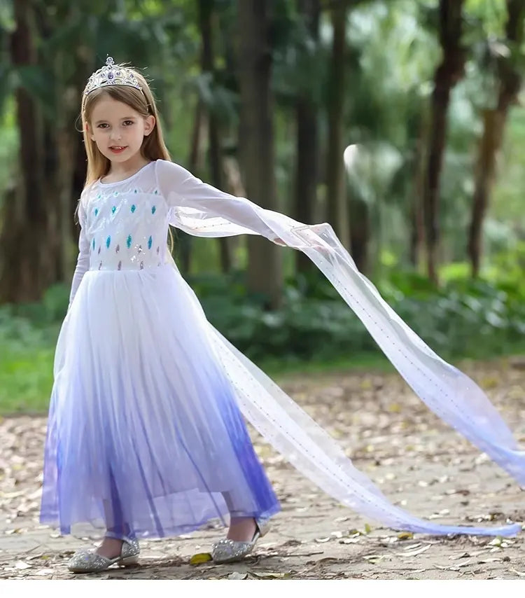 Young girl in a long, light Blue and White snow Queen Princess Sequin Dress With Cape with a flowing train standing in a forest.