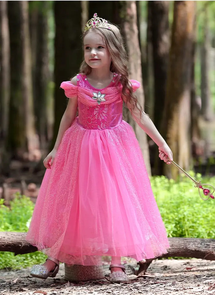 Young girl in a pink princess dress standing in a forest