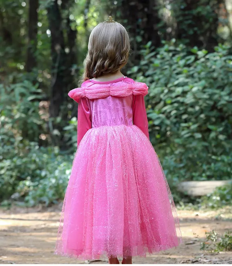 Child wearing a pink dress with a fluffy collar in a forest setting
