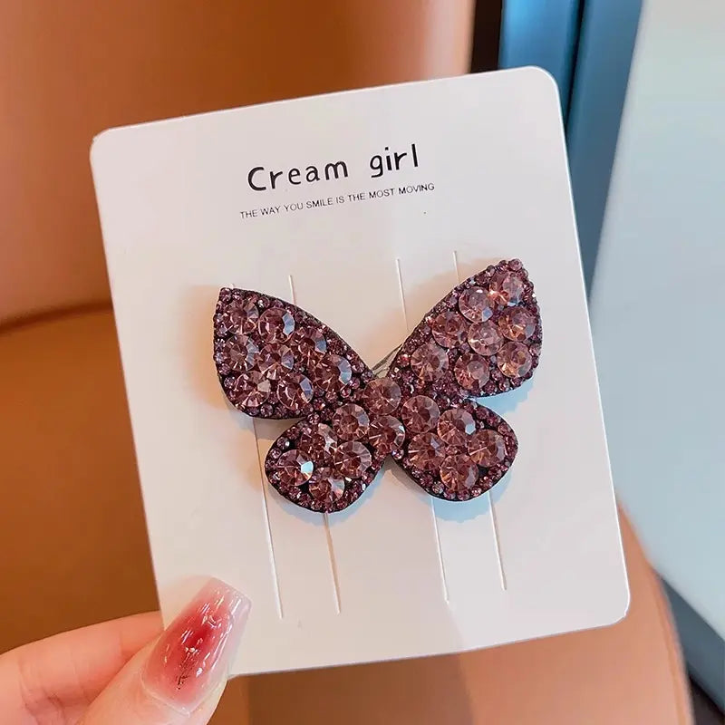 Butterfly-shaped earrings on a  card held by a hand.