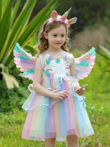 Young girl in a Rainbow Unicorn Fairy Dress costume with wings and horn outdoors.