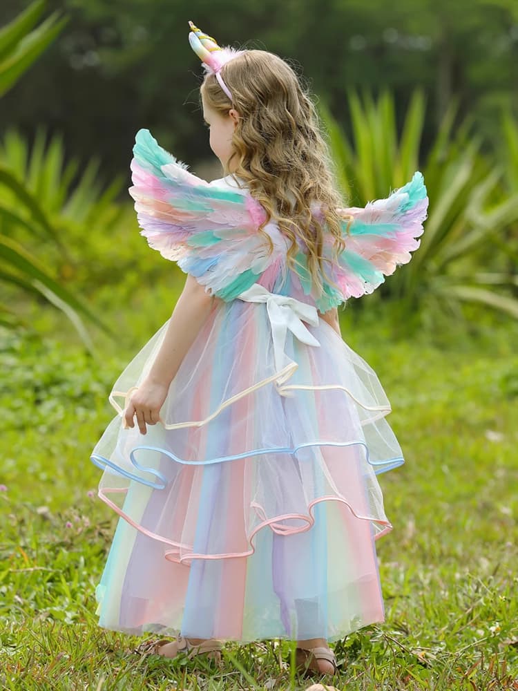Child in a pastel fairy costume with wings standing on grass