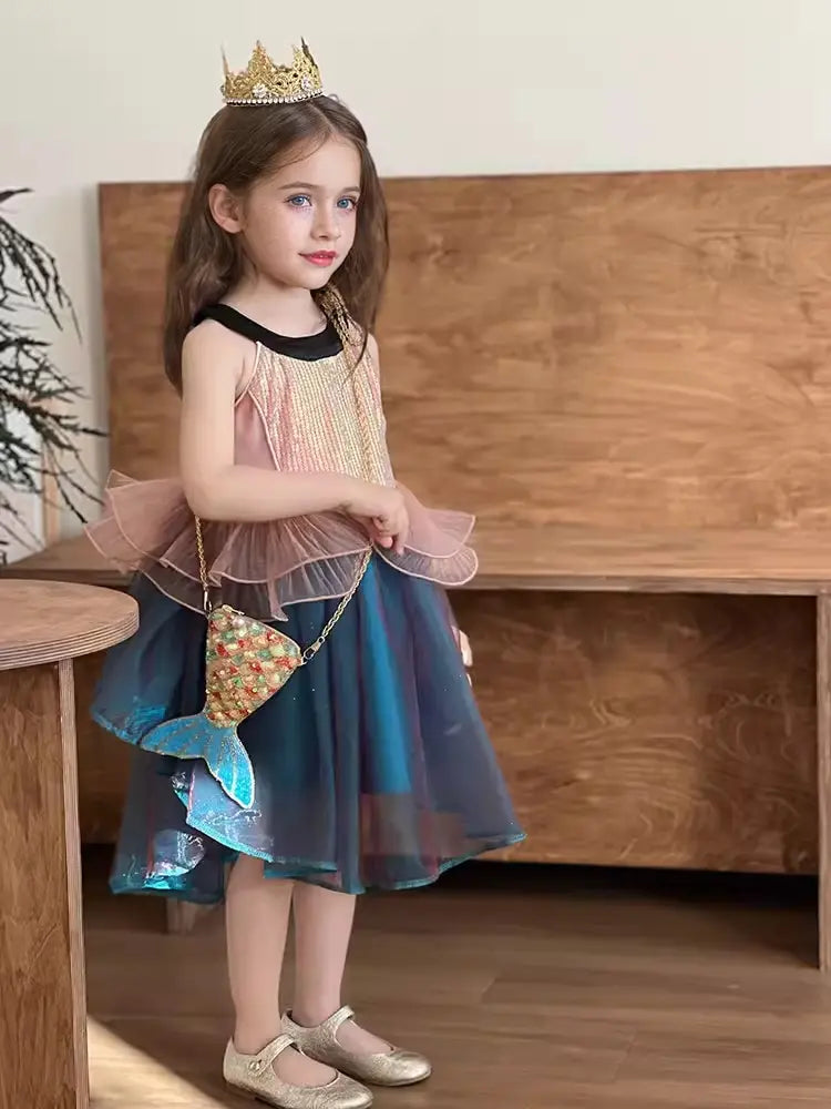 Young girl in a Sleeveless Sea Princess Sequin Blue Tulle  Mermaid Dress  with a tiara, standing indoors.