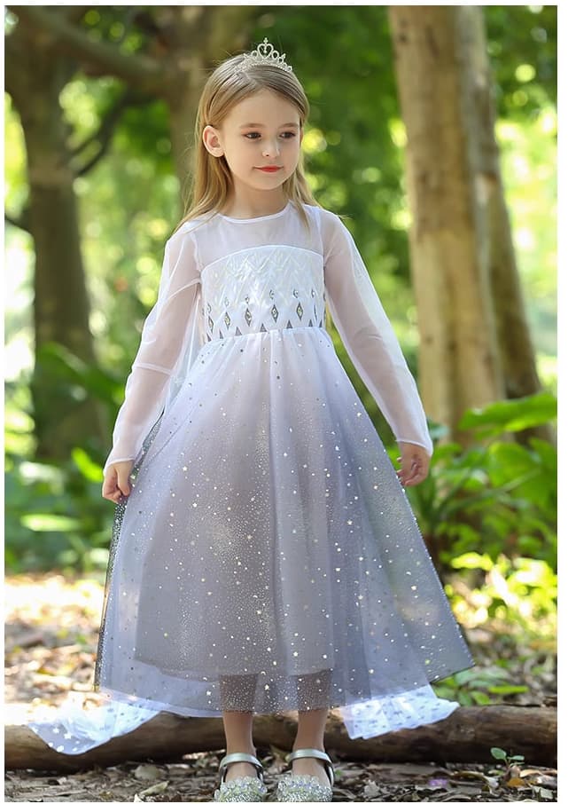 Young girl in a Sparkling Ice-Queen Inspired Princess Dress With Cape with star patterns standing in a forest.