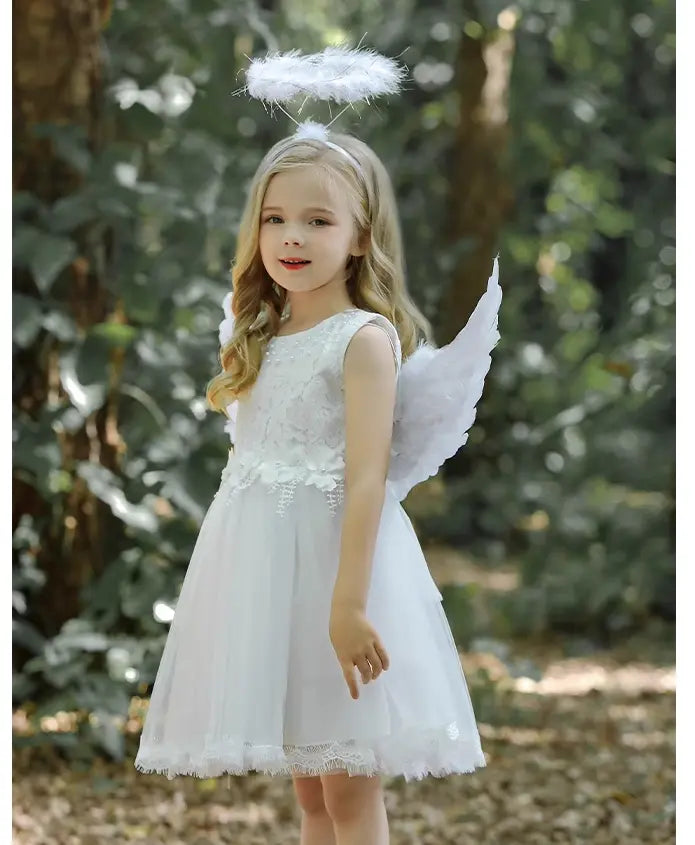Young girl in an angel costume with a white dress, wings, and halo in a forest setting.