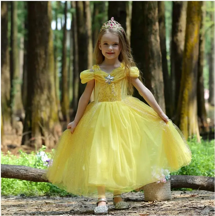 Young girl in a Yellow Tulle Princess Belle Tulle Ball Gown Dress for Girls with a tiara standing in a forest.