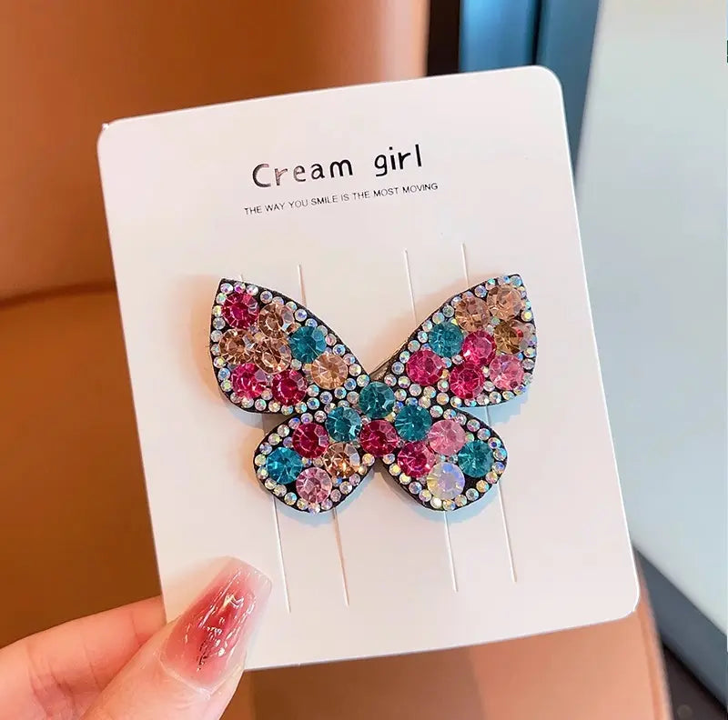 Butterfly-shaped earrings with colorful stones on a  card.
